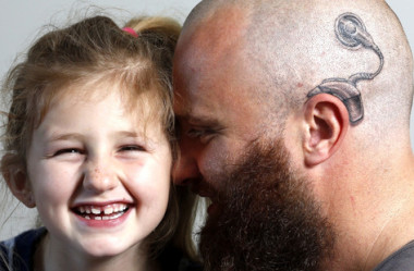 Pai tatua dispositivo auditivo em apoio à filha com implante coclear.